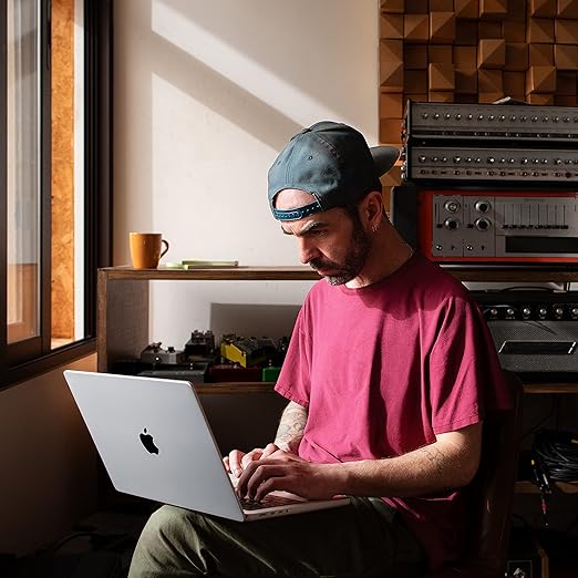 A man working on a laptop in a recording studio.